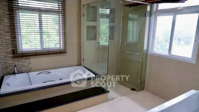 Luxurious bathroom with bathtub and glass shower enclosure, featuring modern design and natural light.