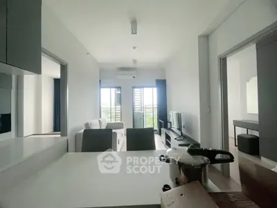 Modern living room with open layout and city view, featuring sleek furniture and natural light.