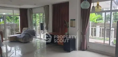 Spacious living room with large windows and garden view, featuring modern furniture and elegant curtains.