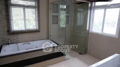 Luxurious bathroom with bathtub and glass shower enclosure, featuring large windows for natural light.