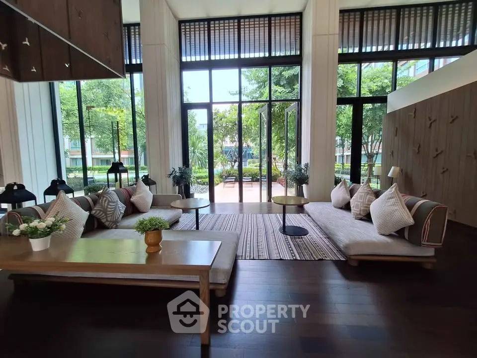 Luxurious living room with floor-to-ceiling windows and elegant decor overlooking lush greenery.