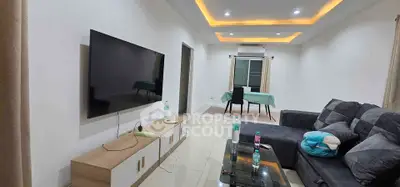 Spacious living room with modern decor and large TV, perfect for family gatherings.