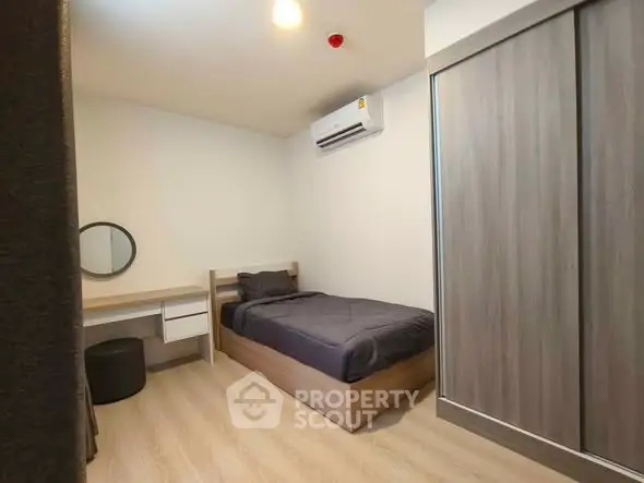 Modern bedroom with sleek design, featuring a single bed, built-in wardrobe, and air conditioning.