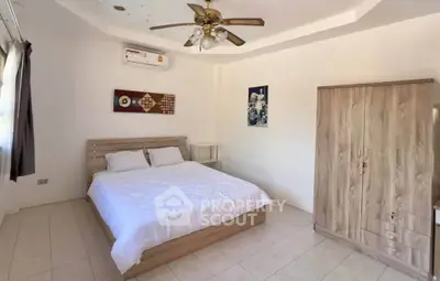 Spacious bedroom with modern decor and ceiling fan in a bright, airy apartment.