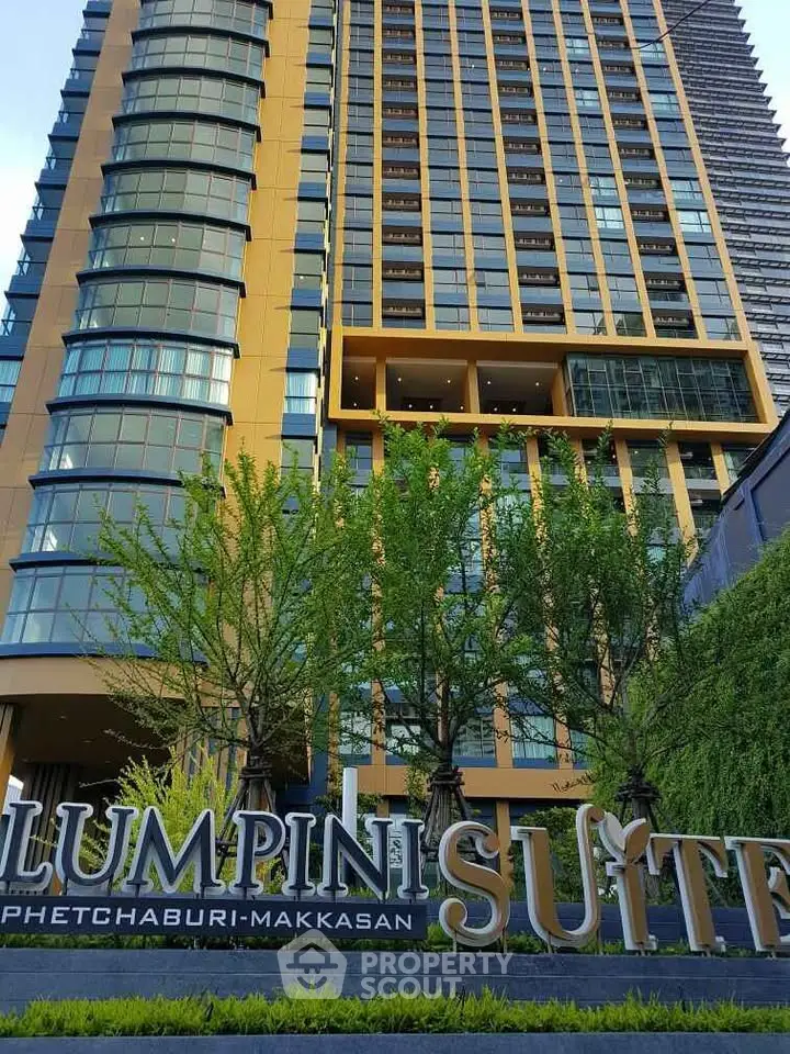 Modern high-rise building with lush greenery at Lumpini Suite Phetchaburi-Makkasan.