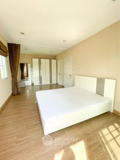 Spacious bedroom with wooden flooring and large wardrobe in modern apartment