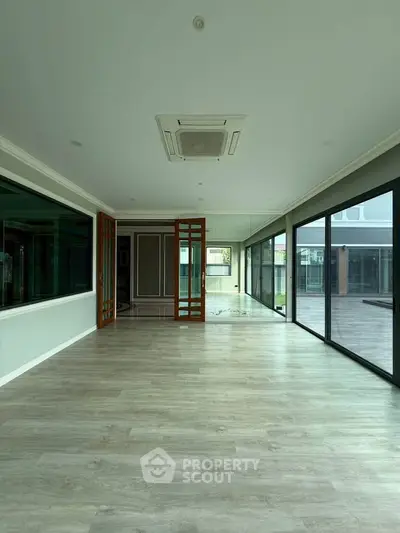 Spacious modern living room with large windows and wooden flooring, perfect for natural light and open views.