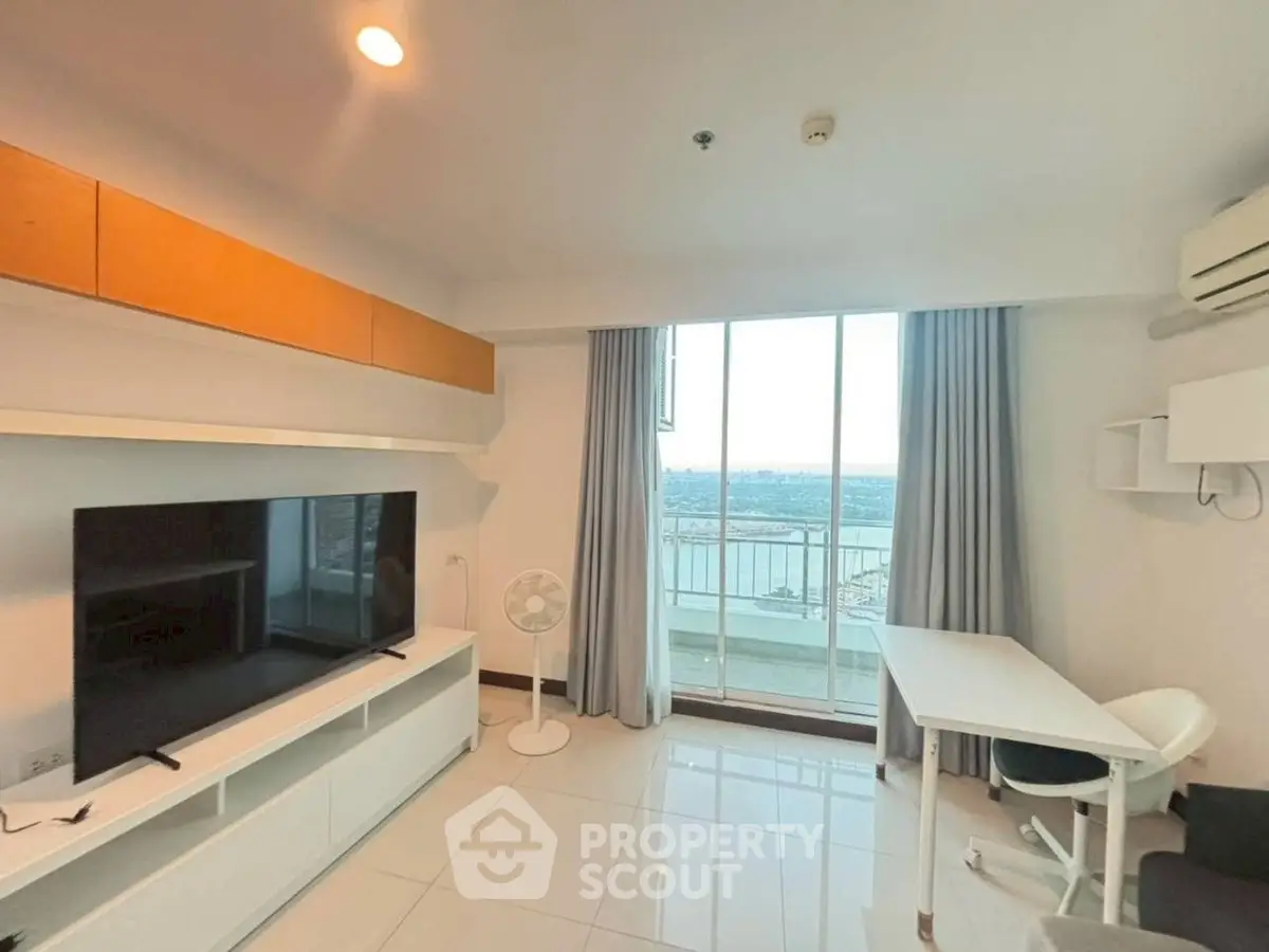 Modern living room with balcony and city view, featuring sleek furniture and ample natural light.