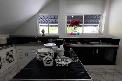 Modern kitchen with sleek black countertops and stacked white dishes, featuring a stylish open layout.
