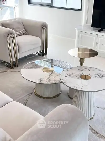 Luxurious modern living room with elegant marble coffee tables and plush seating.