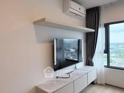 Modern living room with wall-mounted TV and air conditioning, featuring a large window with city view.