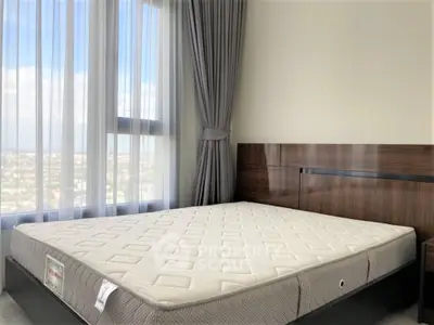 Spacious bedroom with large window and modern bed frame, offering a stunning city view.