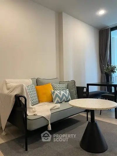 Modern living room with stylish sofa, vibrant cushions, and sleek coffee table in a cozy apartment setting.