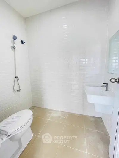 Modern minimalist bathroom with white tiles and sleek fixtures.
