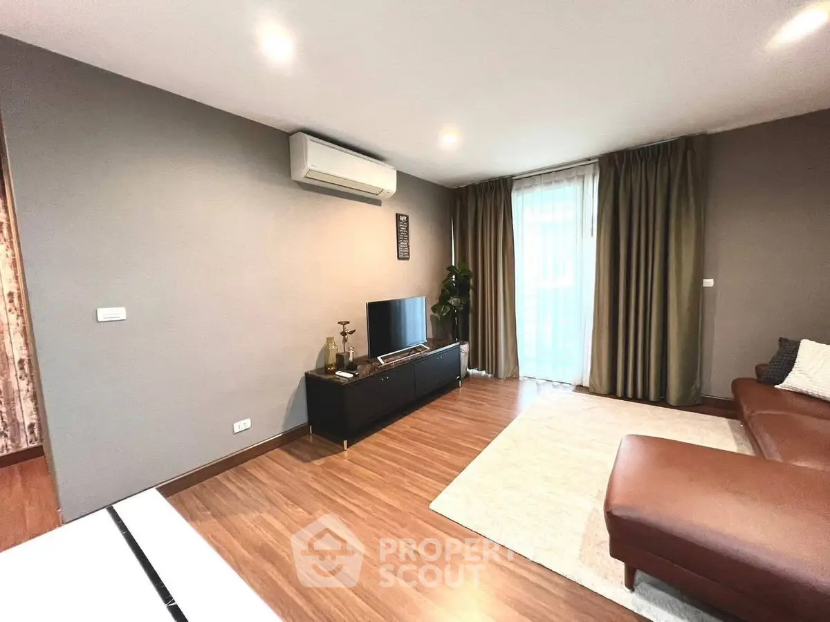 Spacious living room with modern decor and natural light, featuring a sleek air conditioning unit and elegant curtains.