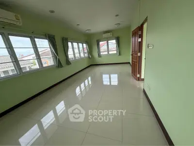 Spacious empty room with large windows and green walls, offering ample natural light and a serene atmosphere.