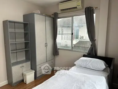 Cozy bedroom with modern wardrobe and air conditioning, featuring a large window for natural light.