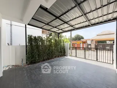 Spacious covered patio with modern roofing and garden view, perfect for outdoor relaxation.