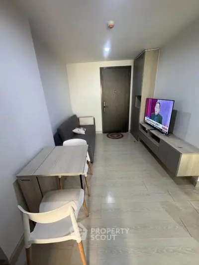 Modern living room with sleek furniture and wall-mounted TV in a cozy apartment.