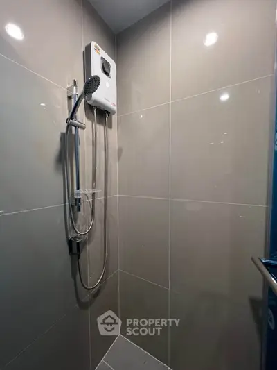 Modern bathroom with sleek shower and water heater in a stylish tiled setting.