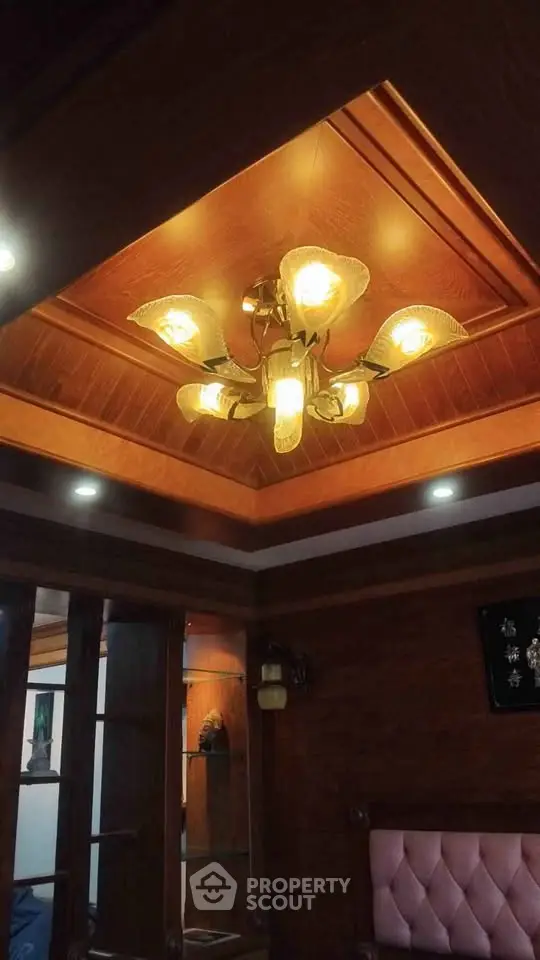 Elegant wooden ceiling with ornate chandelier in luxurious living room.