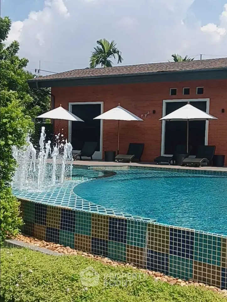 Luxurious poolside view with elegant sun loungers and umbrellas in a serene garden setting.