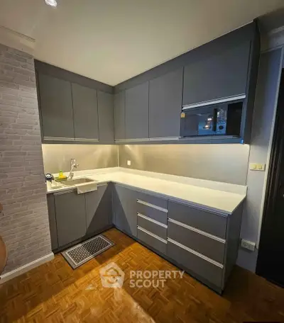 Modern kitchen with sleek cabinetry and parquet flooring, featuring a minimalist design and ample storage space.