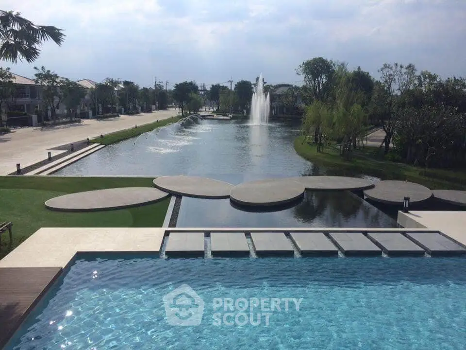 Luxurious residential area with stunning pool and serene water feature view.