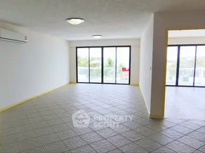 Spacious living room with large windows and balcony access, offering abundant natural light and scenic views.