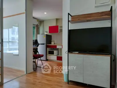 Modern apartment interior with open kitchen and living area featuring sleek furniture and wooden flooring.
