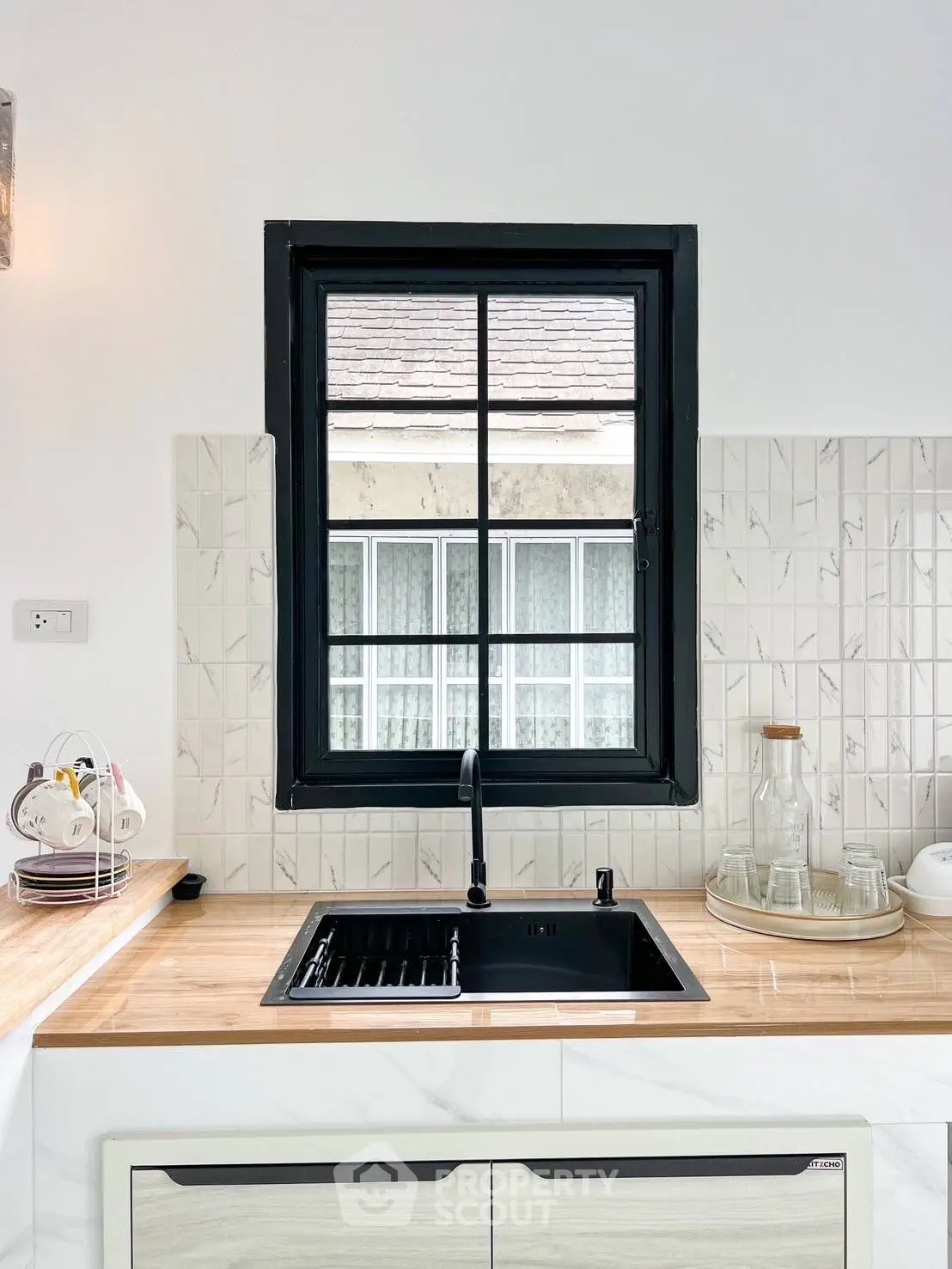 Modern kitchen with sleek black sink and wooden countertop, featuring a window view and stylish backsplash.