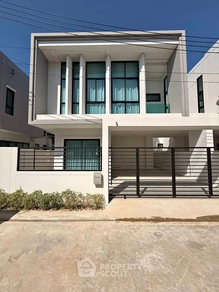 Modern two-story house with sleek facade and large windows in a suburban neighborhood.