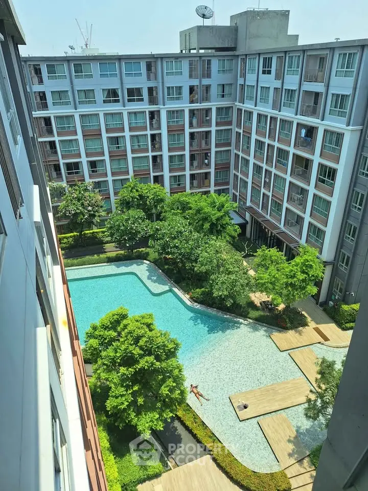 Modern apartment complex with lush garden and inviting swimming pool view.