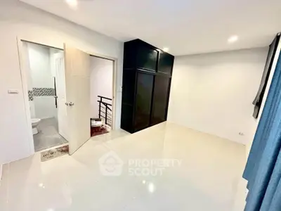 Spacious bedroom with modern closet and en-suite bathroom in a contemporary home.
