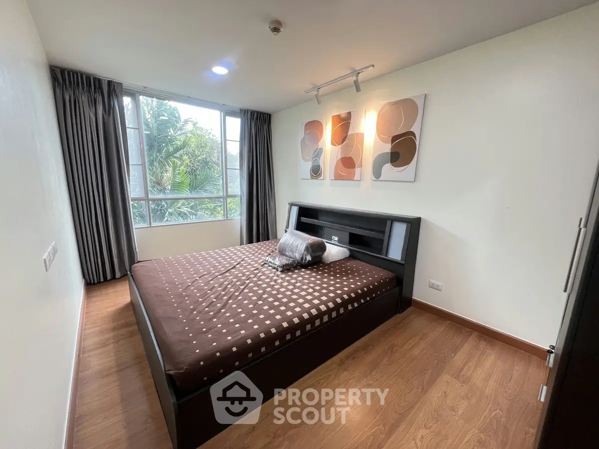 Modern bedroom with large window and stylish decor in a contemporary apartment.