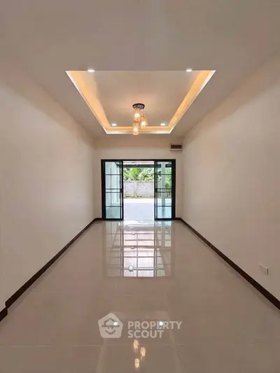 Spacious modern living room with elegant lighting and large glass doors opening to a serene view.