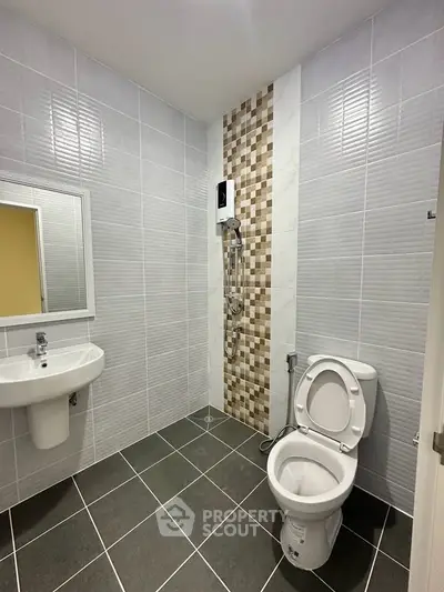 Modern bathroom with sleek tiles and contemporary fixtures, featuring a shower and toilet.