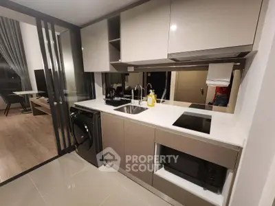 Modern kitchen with sleek cabinetry, built-in appliances, and open layout leading to living area.