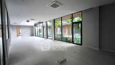 Spacious modern living room with large windows overlooking a lush garden, perfect for natural light lovers.