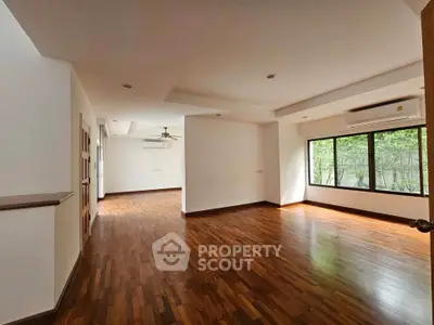 Spacious empty living room with wooden flooring and large windows