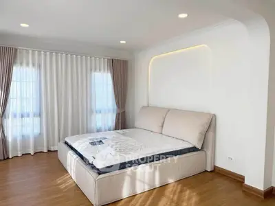 Spacious bedroom with elegant design and natural light, featuring a comfortable bed and stylish curtains.
