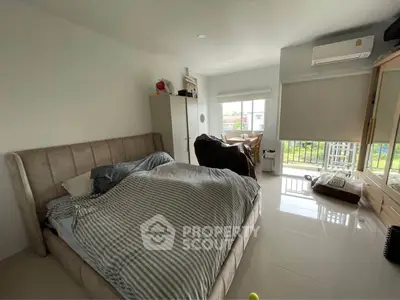 Spacious bedroom with large windows and modern furnishings, featuring a cozy bed and natural light.