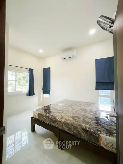 Bright bedroom with air conditioning and large window, featuring modern decor and natural light.