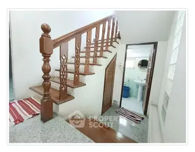 Charming staircase leading to a cozy bathroom with elegant wooden railing and granite steps.