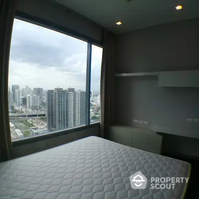 Modern bedroom with stunning city view from large window in high-rise apartment.