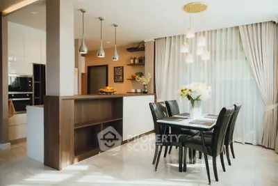 Elegant dining area with modern kitchen, featuring pendant lights and large windows for natural light.