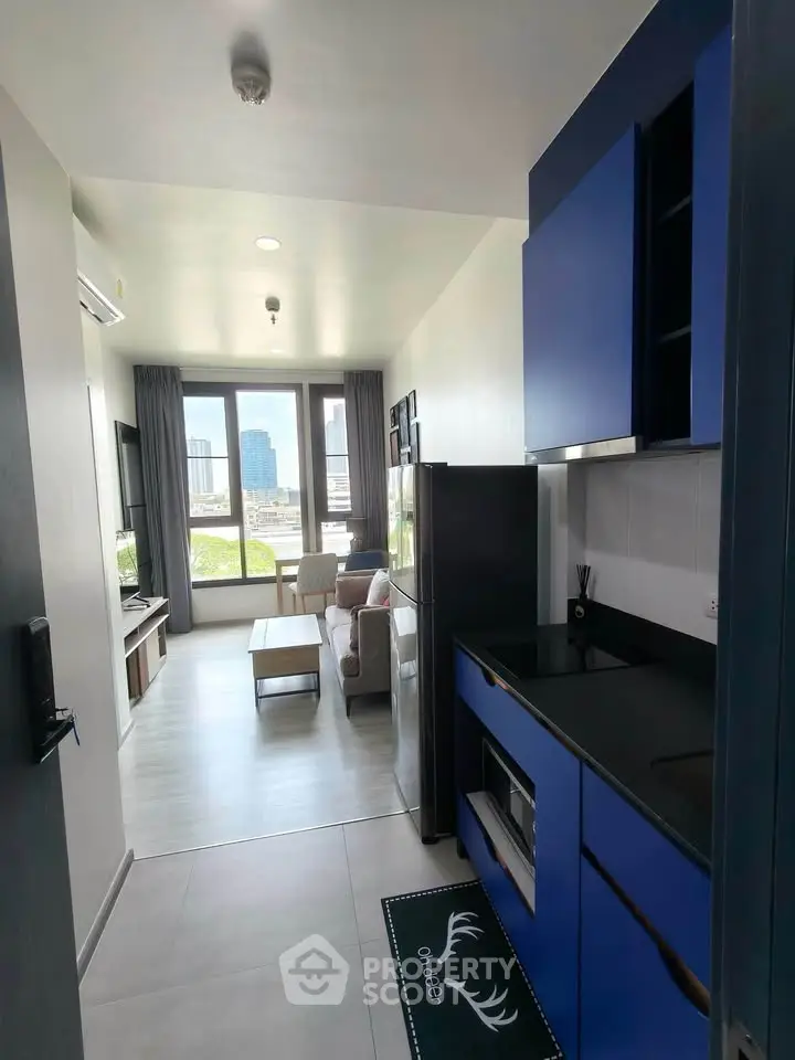 Modern open-layout living room with blue kitchen cabinets and city view.