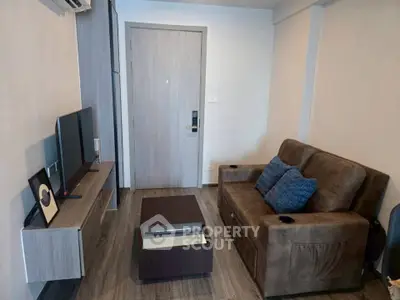 Modern living room with brown sofa, wall-mounted TV, and sleek wooden flooring.