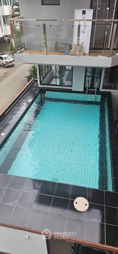 Luxurious rooftop pool with modern design and glass railing, offering a serene urban escape.