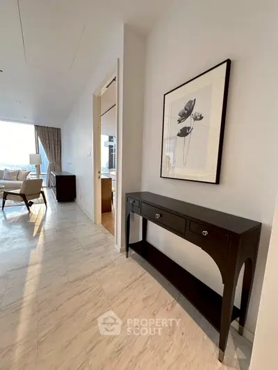 Elegant hallway leading to a spacious living room with modern decor and natural light.